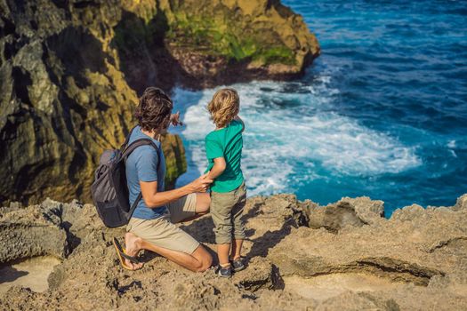 Dad and son tourists against the background of the sea Angel's Billabong in Nusa Penida, Bali, Indonesia. Travel to Bali with kids concept.