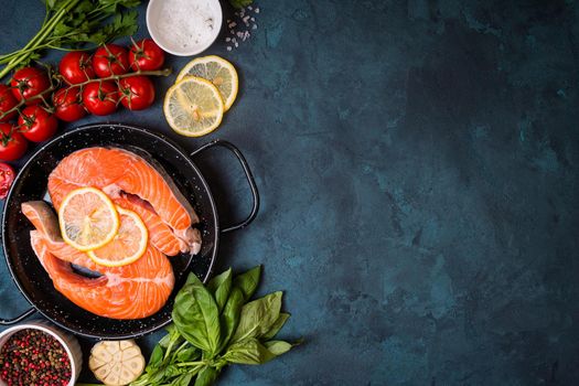 Raw fresh fish with vegetables ready to cook. Raw salmon steak with lemon and spices in a pan. Ingredients for cooking on a concrete background. Space for text. Diet and healthy food. Fish background