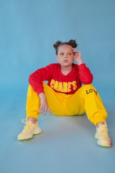 teenage girl in fashion stylish bright clothes. little lady in red and yellow on blue background. makeup and hairdo.