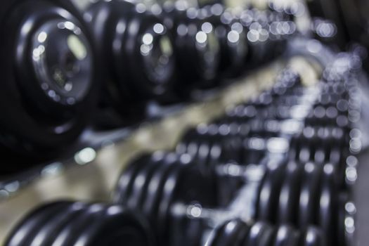 Black dumbbell set. Close up many rubberized dumbbells on rack in sport fitness center , Weight Training Equipment concept