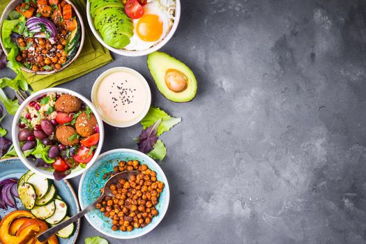 Mixed healthy vegetarian salads with vegetables, sweet potato, falafel, bulgur, avocado, eggs. Assorted buddha bowl salads background. Healthy dinner. Salad in bowl. Making ingredients. Space for text