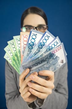 Woman looking at the camera above Kazakhstan money tenge in her hands. Vertical.