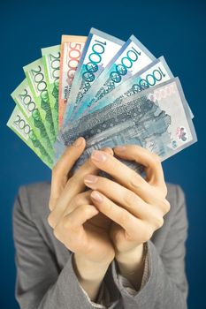 Woman holds Kazakhstan money tenge in front of her. Covers his face with cash. Close-up, Vertical.