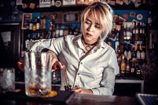 Charming girl barman demonstrates the process of making a cocktail in cocktail bars