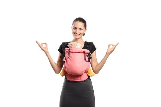 Babywearing beautiful young mother with baby in pink carrier showing zen gesture. Free hands and active motherhood concept.