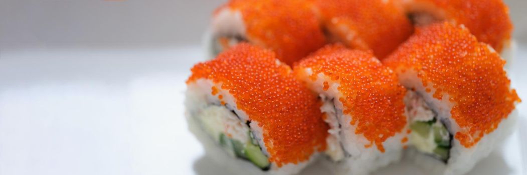 Sushi with orange flying fish caviar on a white plate, close-up. Specific taste, national Japanese cuisine