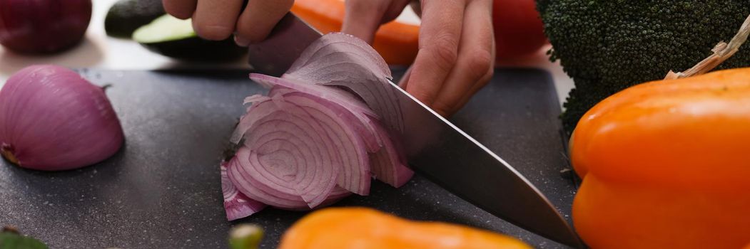 Hands cut onions on a cutting board, organic vegetables close-up. Vegan food preparation, keto diet recipe