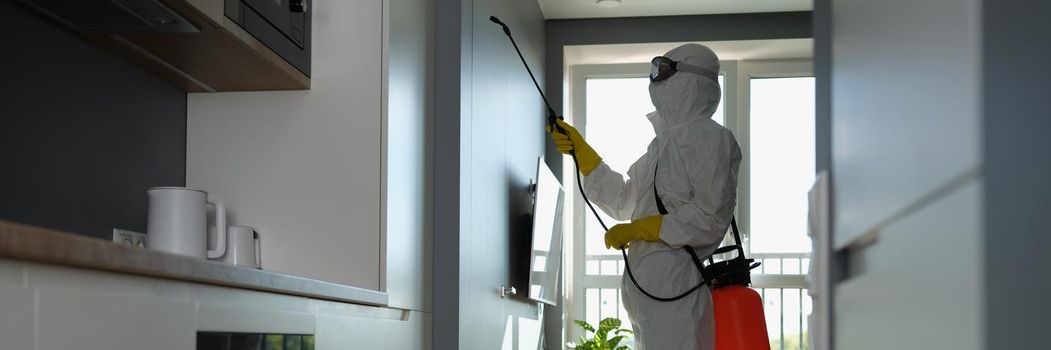 A man in a protective suit sprays an apartment from a balloon. Mosquito protection, antibacterial chemical treatment