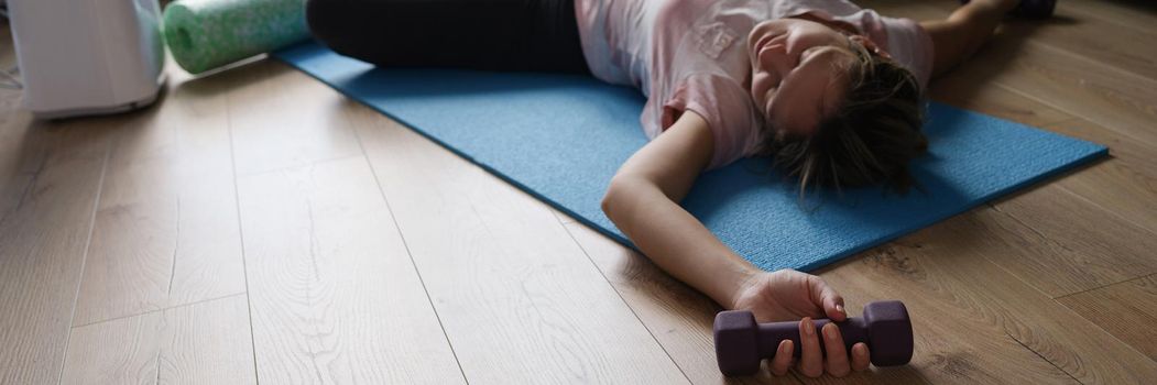 A woman with dumbbells lies on the floor at home, close-up. Improving your figure during a pandemic, fitness