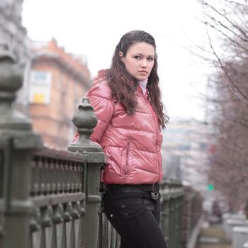 young woman standing on a bridge in the city.