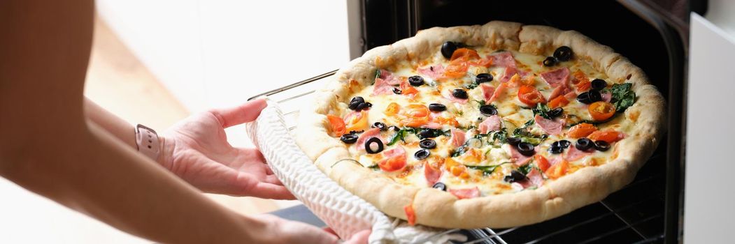 A woman takes out a pizza from the oven, close-up. Homemade pizza without yeast, calorie content. Bake an italian pie