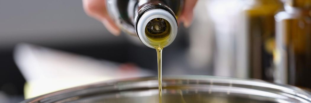 Olive oil is poured from a bottle into a saucepan, close-up. Healthy Cooking, antioxidants. Cholesterol protection
