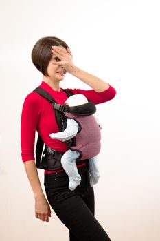 Babywearing confused young mother with baby in substandard carrier. Isolated on white.