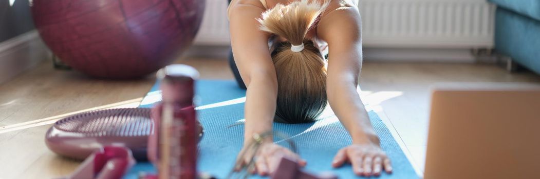 A slender woman is doing stretching on the floor at home. Exercise at home during lockdown, workout pilates