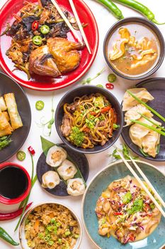 Assorted Chinese food set. Chinese noodles, fried rice, dumplings, peking duck, dim sum, spring rolls. Famous Chinese cuisine dishes on white table. Top view. Chinese restaurant concept. Asian style