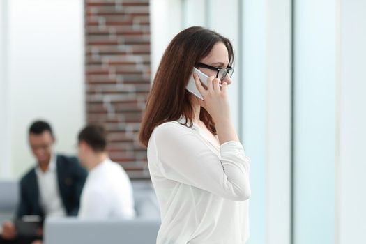 Executive business woman talking on smartphone while standing in office. business concept
