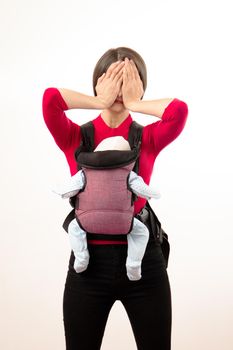 Babywearing depressed young mother with baby in wrong carrier. Isolated on white.