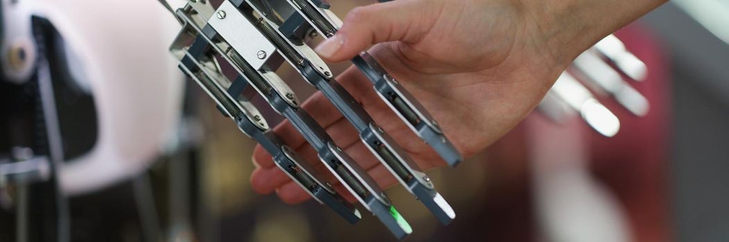 A female hand holds the metal hand of a cyborg, close-up. Steel robot structure, process automation, futuristic equipment