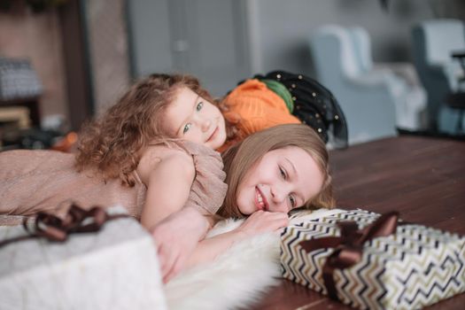 two pretty sisters are having fun in a cozy living room . the concept of Christmas