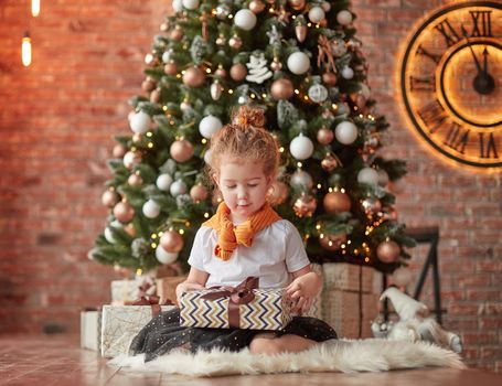 little girl with Christmas gifts sitting near the Christmas tree. the concept of Christmas