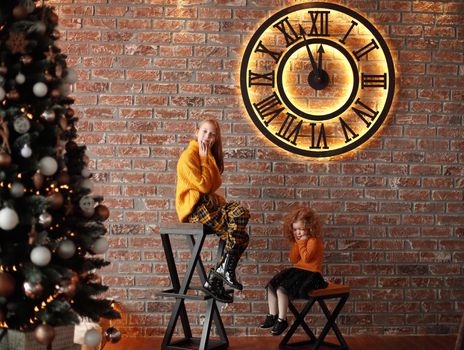 pretty sisters sitting in a stylish living room on Christmas eve . the concept of Christmas