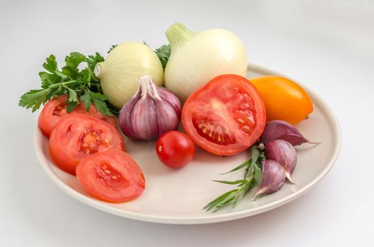 Tomatoes, garlic, onions and greens on a plate.