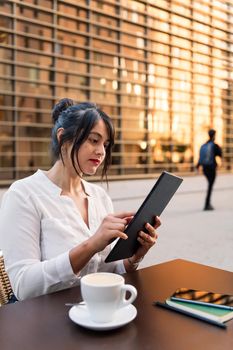 vertical photo of a businesswoman working with a digital tablet on the terrace of a coffee shop, concept of digital entrepreneur and urban lifestyle, copy space for text