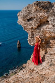 A woman in a red flying dress fluttering in the wind, against the backdrop of the sea