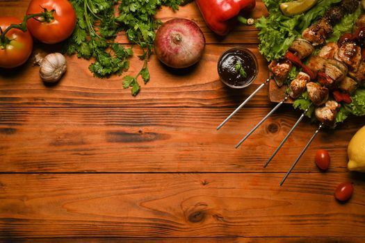 Grilled meat skewers, shish kebab with vegetables on wooden background. Top view with copy space.