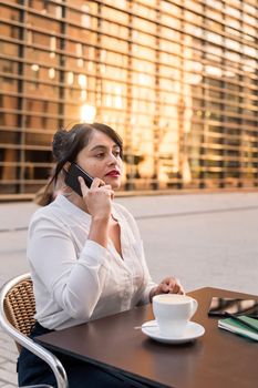 businesswoman talking on the telephone on the terrace of a coffee shop, concept of digital entrepreneur and urban lifestyle, copy space for text