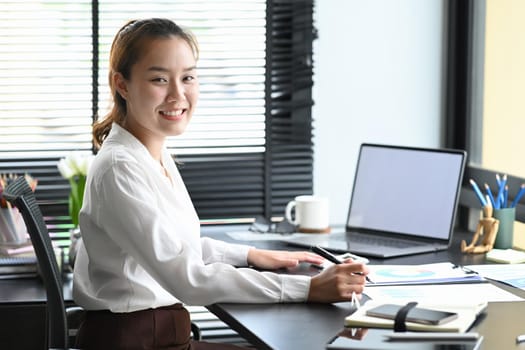 Smiling young entrepreneur using computer laptop in modern home office.