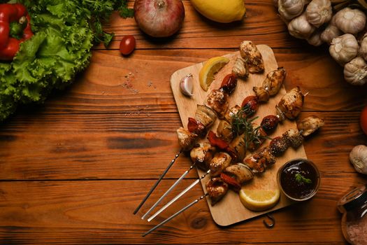 Grilled meat skewers with cherry tomato, sweet pepper, onions and barbecue sauce on wooden board. Top view.