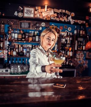 Professional girl barman makes a show creating a cocktail in the nightclub