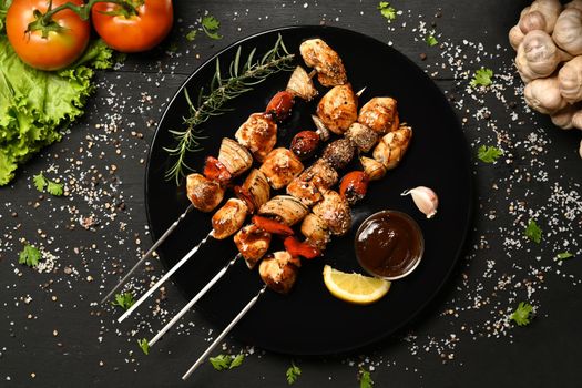 Grilled meat skewers and barbecue sauce on black wooden table. Top view.