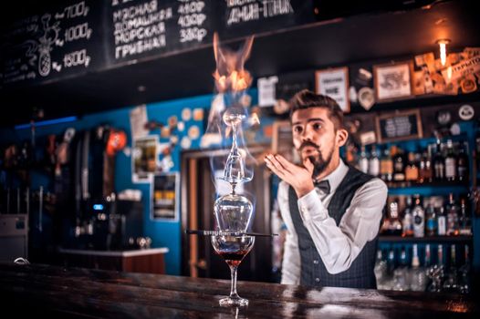 Portrait of bartender makes a show creating a cocktail in pub