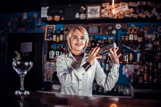 Girl barman formulates a cocktail in the bar