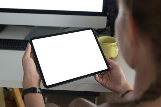Over shoulder closeup view young woman holding digital tablet with empty screen.