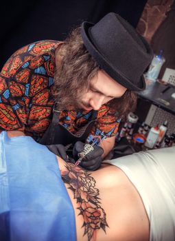 Tattoo master working on professional tattoo machine device in studio./Tattooist makes cool tattoo in tattoo studio.