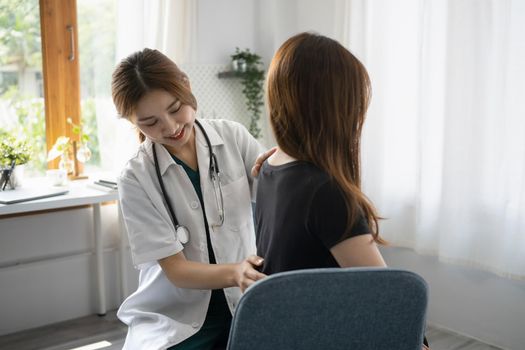 Female physiotherapist examining female patient injured back in modern clinic.