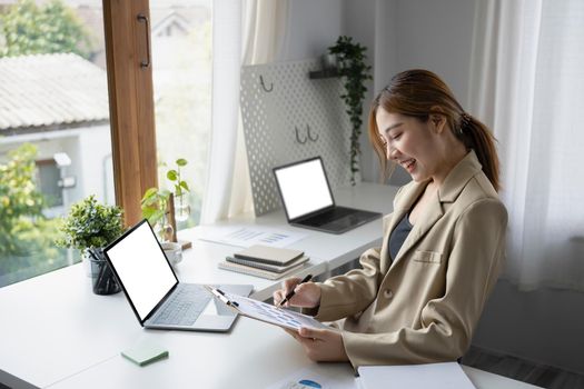 Smiling millennial female employee working with computer laptop at comfortable workplace.
