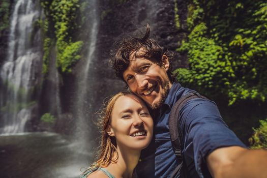 Loving couple at the Sekumpul waterfalls in jungles on Bali island, Indonesia. Bali Travel Concept.