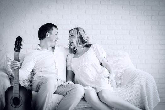 black and white photo in retro style. cheerful husband and wife sitting on sofa in living room