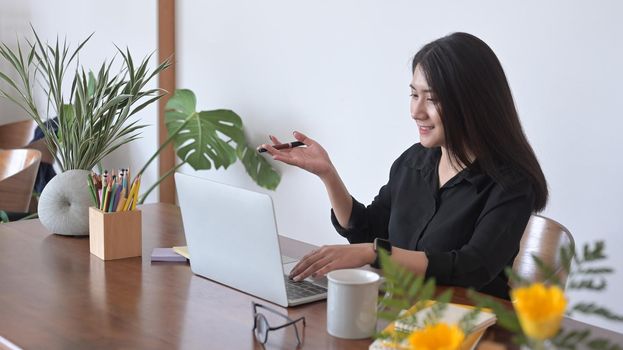 Businesswoman looking at computer laptop screen, watching webinar or doing video chat with colleagues.