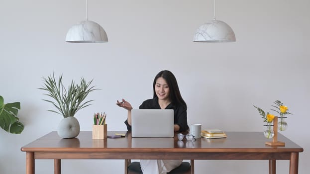 Young business woman having video conference meeting with colleagues, looking at laptop computer screen.