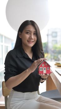 Attractive young woman hands holding house model. Real estate insurance and banking concept.