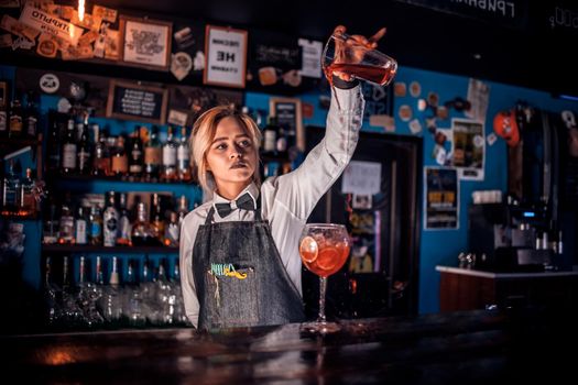 Girl barman creates a cocktail in the porterhouse