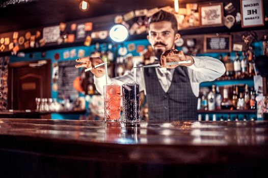 Confident bartending adds ingredients to a cocktail behind bar
