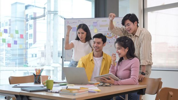 Startup business team celebrating corporate victory together in office.