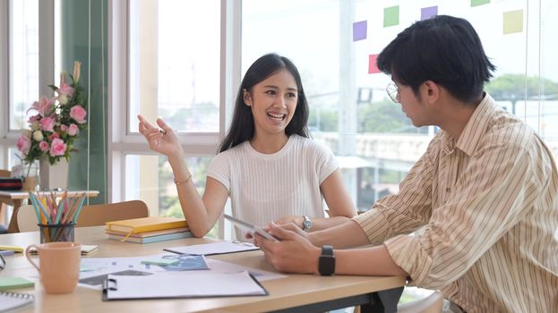 Beautiful female employee explaining new online project, discuss business ideas with her business colleague.