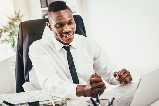 Successful African businessman celebrating success with fists in the modern office.
